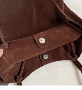 Close-up of dark brown suede handbag featuring a silver cylindrical magnetic clasp closure