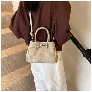 Classic metal twist lock and stud detail on the beige textured faux leather handbag