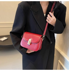 Détail du petit sac bandoulière rouge avec fermoir doré sur une veste noire