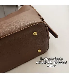 Close-up of brown pebbled leather bag bottom featuring protective gold metal studs