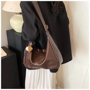 Detail of a dark brown leather hobo bag with adjustable strap and strawberry charm