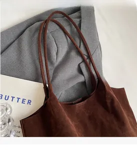 Detail of dark brown matte suede tote bag with slim handles and minimalist urban texture