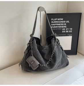 Détail d'un cabas en jean délavé avec chaîne argentée et mini pochette zippée