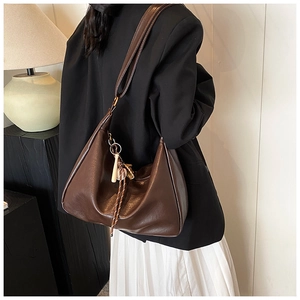 Detail of dark brown faux leather crescent bag with wooden bead and tassel charm