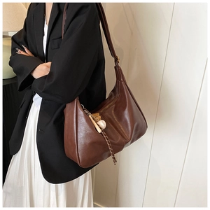Brown vintage hobo bag with baseball charm detail shown on a stylish model