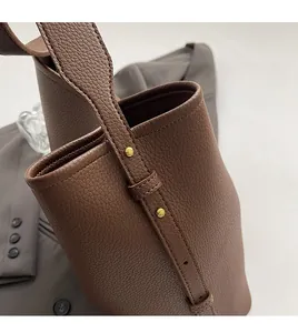 Close-up of brown pebbled leather texture with handcrafted stitching and gold rivets