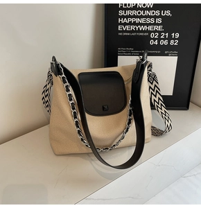 Detail of a beige tote bag featuring three versatile straps and textured fabric panels