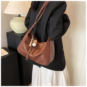 Detail of dark brown vintage hobo bag in soft PU leather with baseball charm accessory