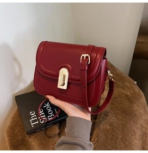 Détail du sac à rabat en cuir bordeaux avec boucle dorée et décor élégant