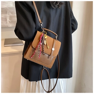 Close-up of retro brown crossbody bag featuring dual-material stitching and metal magnetic clasp