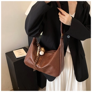 Close-up of brown vintage leather tote with baseball charm and matte finish on shoulder