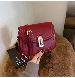 Détail d'un petit sac carré rouge avec fermoir rotatif doré et bandoulière réglable