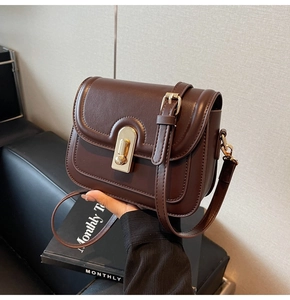 Détail d'un sac bandoulière en cuir marron foncé avec fermoir rotatif doré vintage