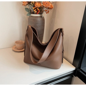Detailed close-up of brown litchi grain leather hobo bag on elegant marble surface