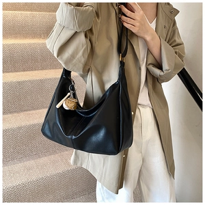 Detail of a black large-capacity PU leather tote bag with soft folds and side pendant