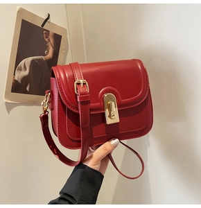Détail d'un sac bandoulière rouge en cuir avec fermoir rotatif en métal doré chic