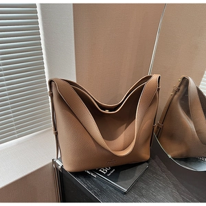 Detail of brown litchi grain leather bag with embossed logo and soft texture finish