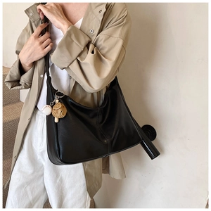 Detail of black crescent hobo bag with baseball glove pendant on matte leather
