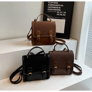 Three vintage buckle satchels in black, brown, and dark coffee on a white display stand
