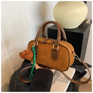 Détail d'un mini sac à main en daim marron avec pendentif ours et détails dorés