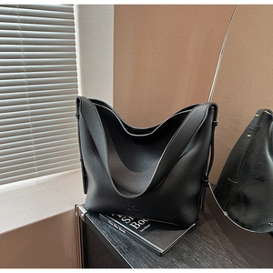Detail view of black lychee grain leather bucket bag with soft texture and logo embossing