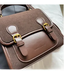 Close-up of brown vintage crossbody bag with gold metal buckles and leather texture