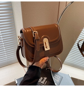 Détail d'un sac bandoulière en cuir marron avec fermoir rotatif doré et coutures fines