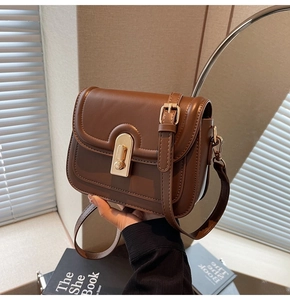 Détail du sac à bandoulière en cuir marron caramel avec fermoir doré et surpiqûres