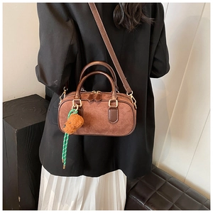 Détail d'un sac à main vintage en cuir marron dépoli avec un porte-clé peluche chiot