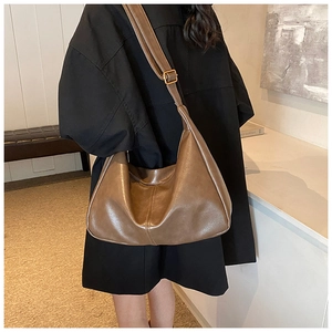 Detailed view of the brown leather texture and vertical stitching on the vintage tote bag