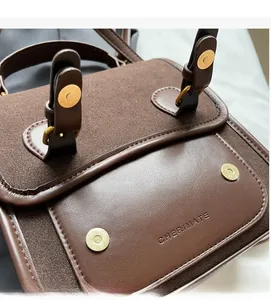 Close-up of golden magnetic closure on brown leather and suede messenger bag
