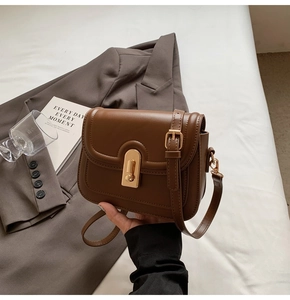 Détail de petit sac carré marron vintage avec fermoir rotatif ovale doré et texture en similicuir