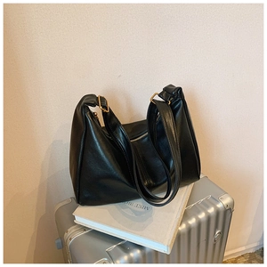 Detail view of black faux leather tote texture and golden hardware on a silver suitcase