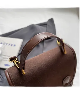 Detailed close-up of brown faux leather tote handle with vintage gold hardware and stitching