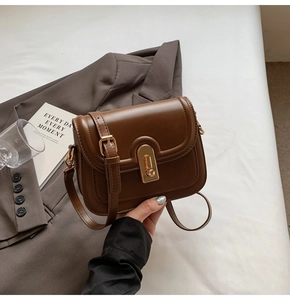 Détail du sac bandoulière marron vintage avec fermoir doré et texture cuir lisse