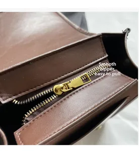 Detail shot of smooth golden metal zipper closure on brown leather handbag