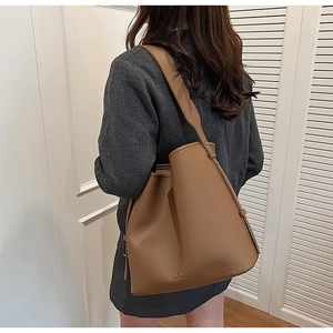 Detailed macro view of brown pebbled leather tote bag with embossed brand logo
