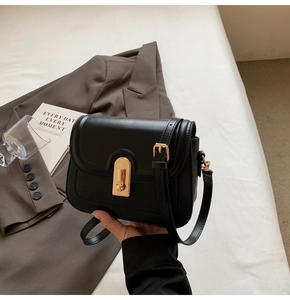 Détail du sac en cuir noir mat avec fermoir en métal doré et texture raffinée