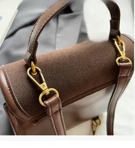 Detail of dark brown leather and coffee suede stitching with antique gold hardware