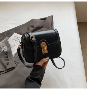 Détail du sac bandoulière noir avec finition cuir texturé et fermoir rotatif doré