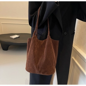 Minimalist dark brown suede tote bag styled with a black coat in a modern interior setting