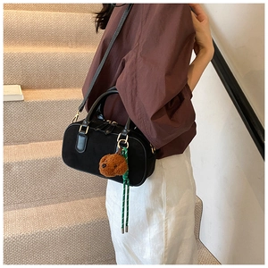 Sac à bandoulière noir mat avec charm ours en peluche marron porté par un mannequin