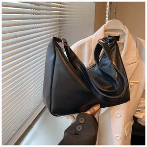 Detail view of black faux leather tote bag showing wide strap and gold metal buckle