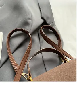 Close-up of golden metal hooks and comfortable straps on a brown suede shoulder bag