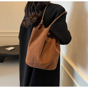Close-up of brown suede tote bag featuring decorative knot shoulder strap detail