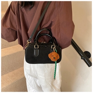 Mannequin portant un sac Boston en daim noir avec un charmant chien en peluche