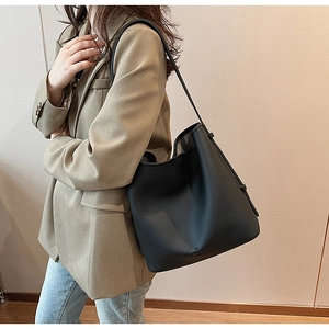 Detail of black pebbled leather bucket bag on model with khaki blazer and jeans