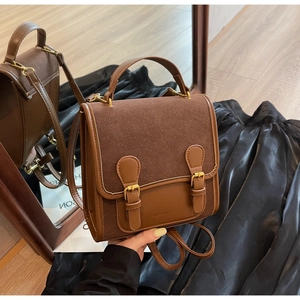 Detail of vintage brown shoulder bag showing smooth and matte leather textures with buckles