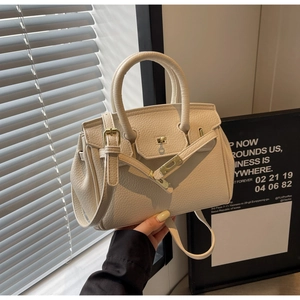 Detail of off-white lychee pattern leather handbag with classic metal twist lock and handle