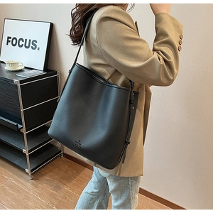Detail of black lychee texture leather bucket bag with FANTON STORIES logo and strap